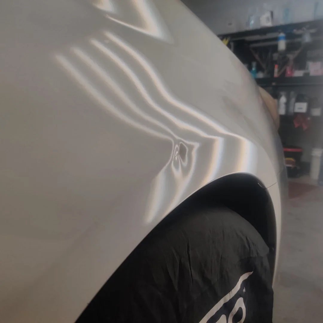 Sharp crease dent on silver vehicle before PDR repair Ontario